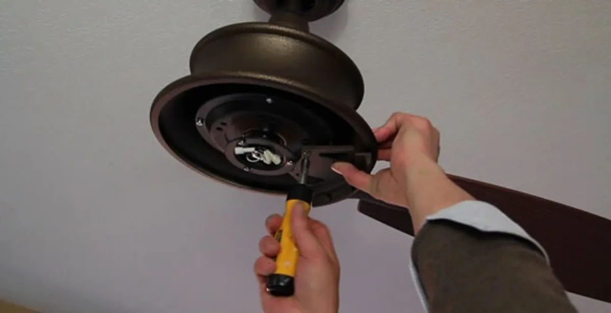 Electrician installing ceiling fan mounting bracket and fixture in Olathe, KS