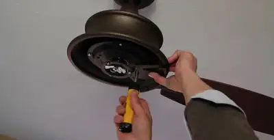 Electrician installing ceiling fan mounting bracket and fixture in Olathe, KS