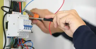 Electrician installing and adjusting circuit breakers in an electrical panel in Olathe, KS