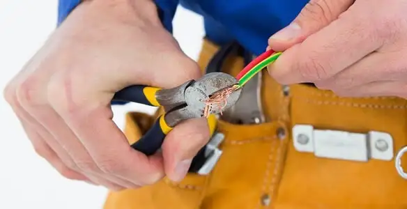 licensed electrician securing electrical wiring with professional tools during service work in Olathe, KS