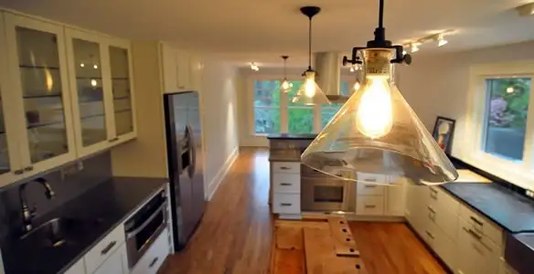 Residential electrician installing modern indoor light fixture in a home in Olathe, KS