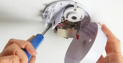 Certified technician wiring smoke detector during installation in Olathe, KS